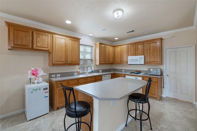 kitchen featuring a breakfast bar, sink, a center island, crown molding, and white appliances