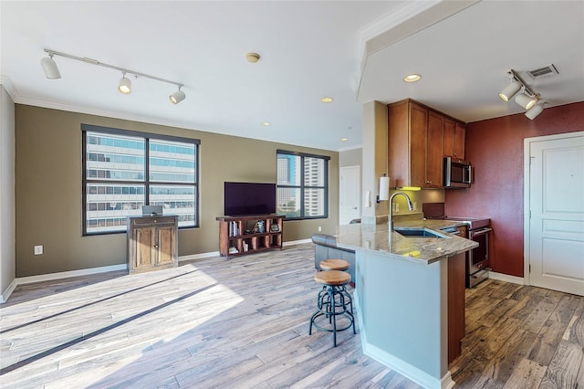 kitchen with light stone counters, appliances with stainless steel finishes, sink, and light hardwood / wood-style flooring