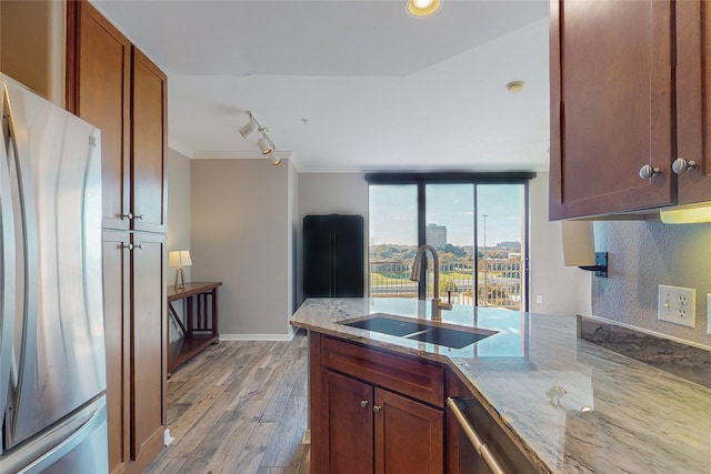 kitchen featuring sink, stainless steel refrigerator, light stone counters, ornamental molding, and light hardwood / wood-style floors