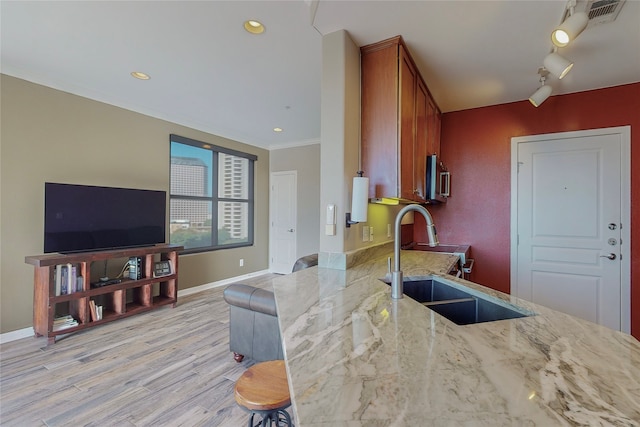 kitchen featuring sink, light stone counters, crown molding, light wood-type flooring, and kitchen peninsula