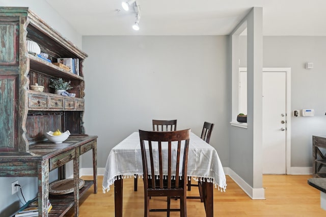 dining area with light hardwood / wood-style floors and rail lighting