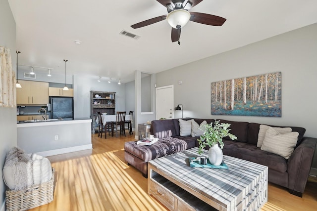 living room with sink, ceiling fan, and light wood-type flooring