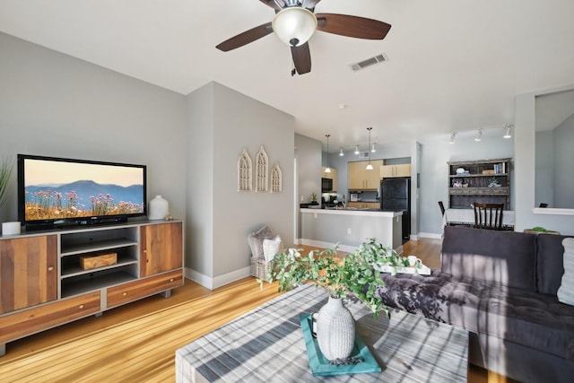 living room with light hardwood / wood-style floors, rail lighting, and ceiling fan