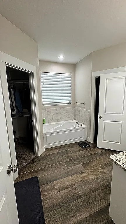 bathroom with vanity, hardwood / wood-style floors, and a tub to relax in