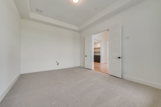 carpeted empty room with a tray ceiling