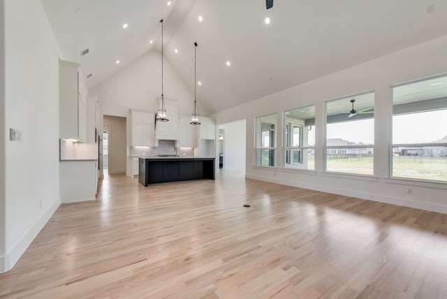 unfurnished living room featuring high vaulted ceiling, light wood-type flooring, sink, and ceiling fan