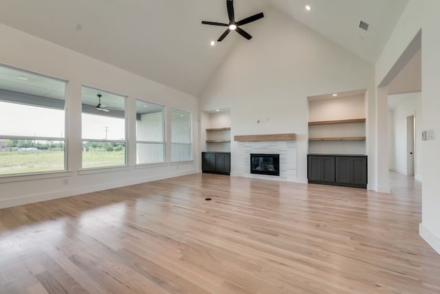 unfurnished living room featuring built in features, ceiling fan, high vaulted ceiling, a fireplace, and light hardwood / wood-style floors