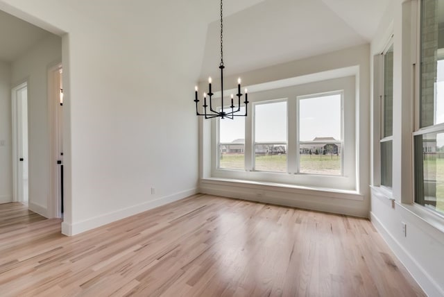 unfurnished dining area featuring lofted ceiling, light hardwood / wood-style floors, and a notable chandelier