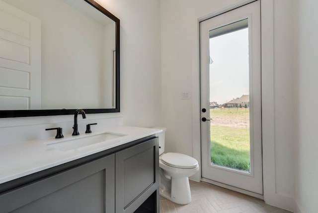 bathroom with parquet flooring, vanity, and toilet