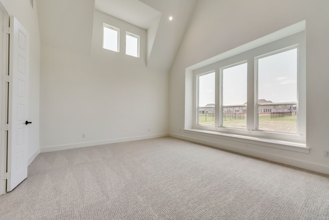 carpeted spare room featuring a towering ceiling and a healthy amount of sunlight