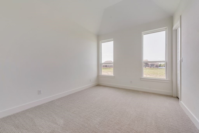 empty room featuring vaulted ceiling and light carpet