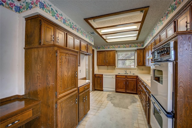 kitchen featuring sink, white appliances, and a textured ceiling