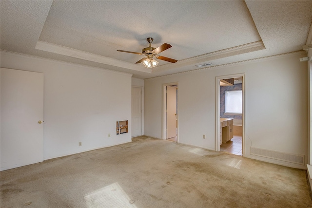 unfurnished bedroom with light colored carpet, a textured ceiling, and a tray ceiling