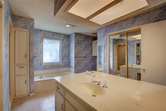 bathroom with vanity, a tub to relax in, tile patterned floors, and a textured ceiling