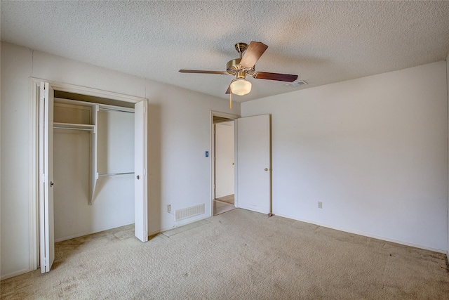 unfurnished bedroom with ceiling fan, light colored carpet, a textured ceiling, and a closet