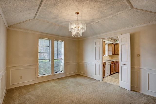 carpeted empty room with vaulted ceiling, an inviting chandelier, sink, crown molding, and a textured ceiling