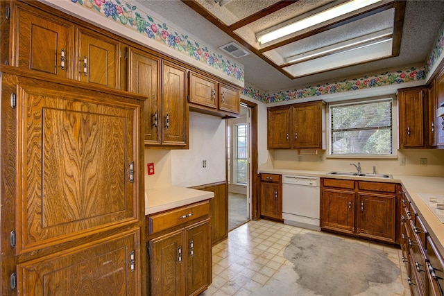 kitchen with white dishwasher, sink, and a textured ceiling