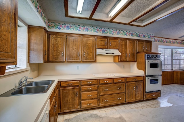 kitchen with sink, a textured ceiling, and white appliances