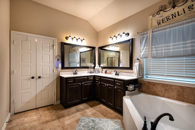 bathroom with vaulted ceiling, a tub, vanity, and tile patterned floors