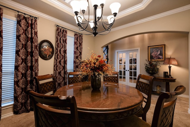 dining area with a chandelier, ornamental molding, light colored carpet, a raised ceiling, and french doors