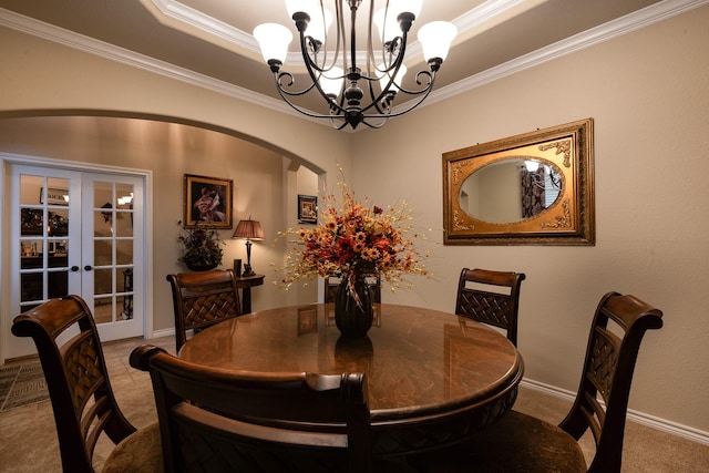 dining room featuring crown molding, a raised ceiling, an inviting chandelier, and french doors