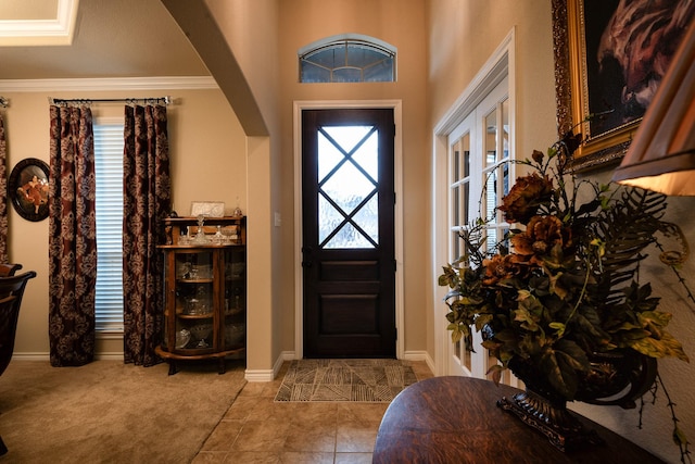 entryway with ornamental molding and light carpet