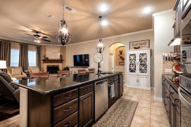 kitchen featuring sink, a kitchen island with sink, dark brown cabinets, stainless steel appliances, and ornamental molding