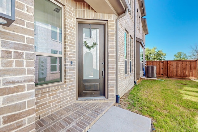 property entrance featuring central AC unit and a lawn