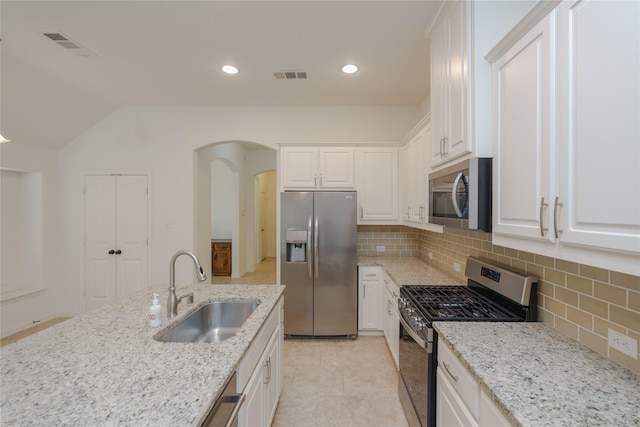 kitchen with sink, light stone countertops, white cabinets, and appliances with stainless steel finishes