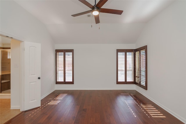 empty room with dark hardwood / wood-style flooring, vaulted ceiling, and a wealth of natural light