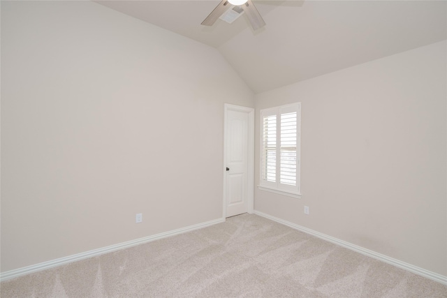 empty room with ceiling fan, vaulted ceiling, and light carpet