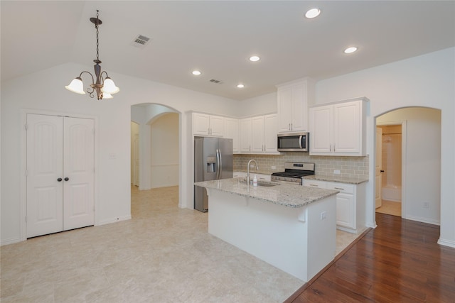 kitchen with sink, white cabinetry, light stone counters, an island with sink, and stainless steel appliances