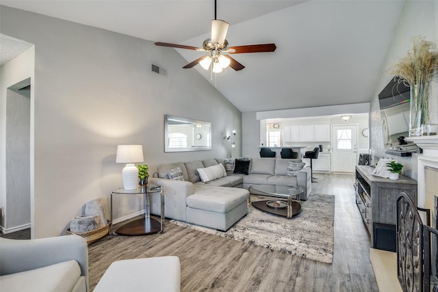 living room featuring ceiling fan, high vaulted ceiling, and light wood-type flooring