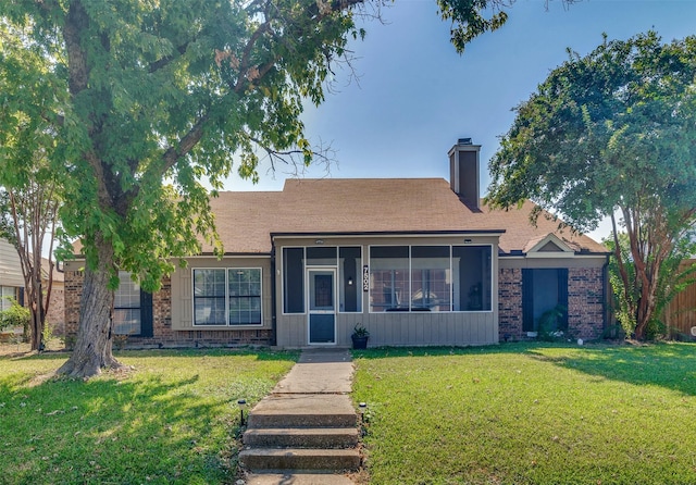 ranch-style home featuring a sunroom and a front lawn