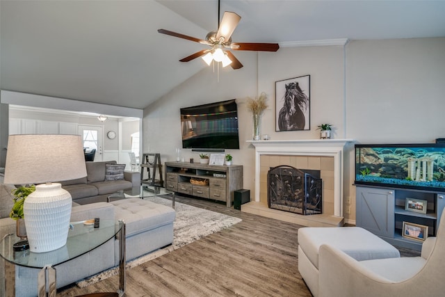 living room featuring a tiled fireplace, hardwood / wood-style floors, vaulted ceiling, and ceiling fan