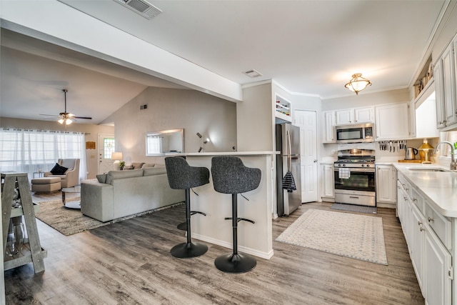 kitchen with dark wood-type flooring, sink, white cabinetry, vaulted ceiling, and appliances with stainless steel finishes