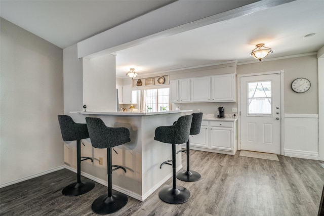 7502 Atlantic Dr, Rowlett, TX 75088 - kitchen with light wood-type flooring, a kitchen bar, white cabinets, and healthy amount of natural light