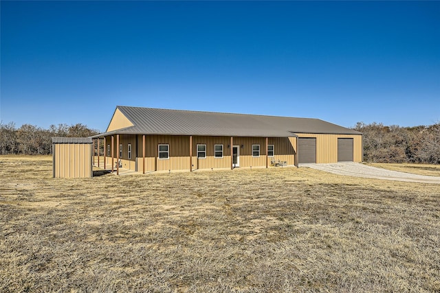 view of front of house featuring a garage, metal roof, a front lawn, and an outbuilding