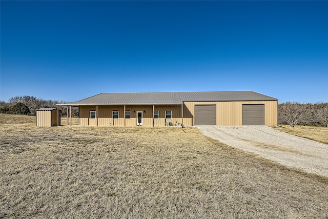 view of front of house with a garage, metal roof, an outbuilding, covered porch, and a front lawn