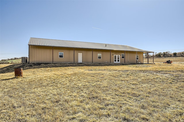 back of house with metal roof and a lawn