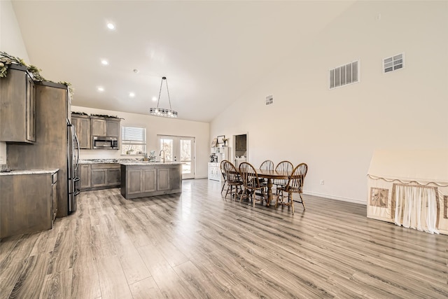 kitchen with light wood finished floors, visible vents, appliances with stainless steel finishes, a center island, and hanging light fixtures