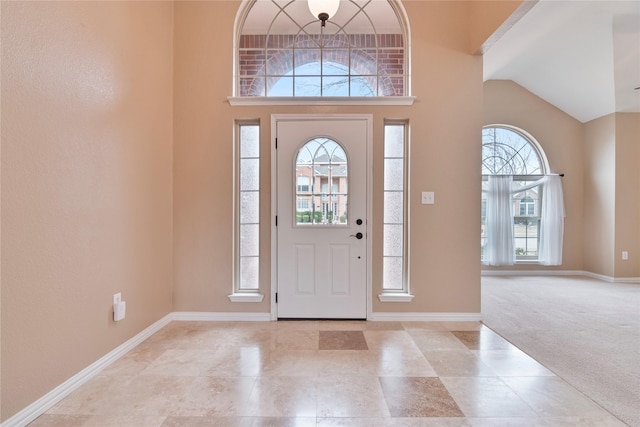 carpeted foyer entrance featuring high vaulted ceiling