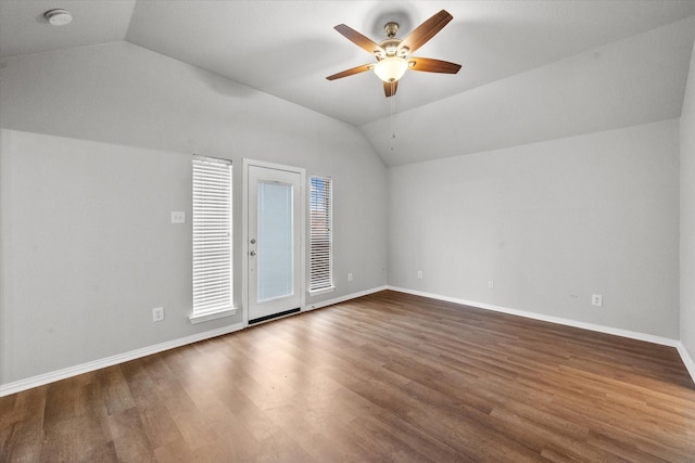 empty room with dark hardwood / wood-style flooring, vaulted ceiling, and ceiling fan