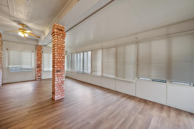 unfurnished room with ceiling fan, beam ceiling, wood-type flooring, brick wall, and ornate columns