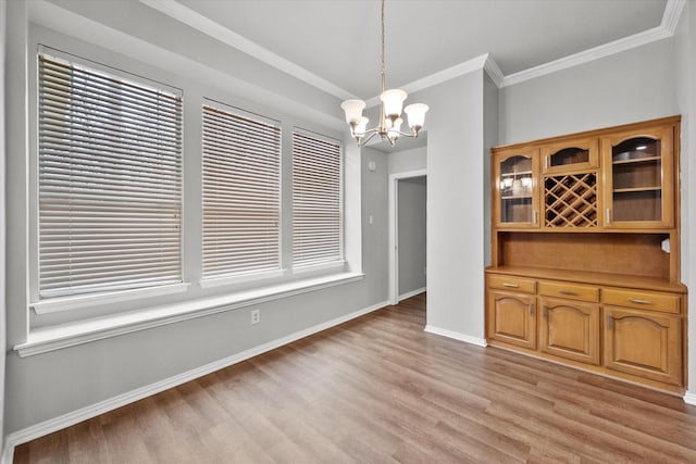 unfurnished dining area featuring a notable chandelier, crown molding, and light wood-type flooring