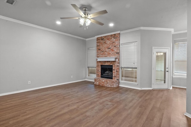 unfurnished living room with wood-type flooring, a brick fireplace, ceiling fan, and crown molding