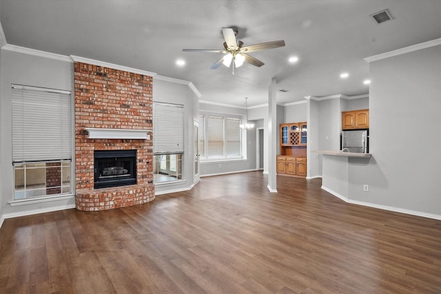 unfurnished living room featuring dark hardwood / wood-style flooring, crown molding, ceiling fan with notable chandelier, and a fireplace