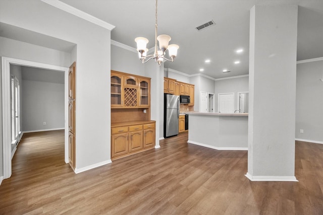 kitchen with a notable chandelier, pendant lighting, stainless steel fridge, and light hardwood / wood-style flooring