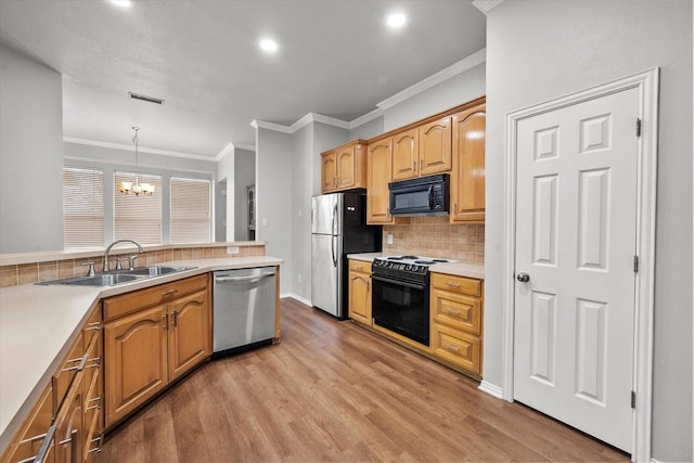 kitchen with decorative light fixtures, tasteful backsplash, sink, a notable chandelier, and black appliances