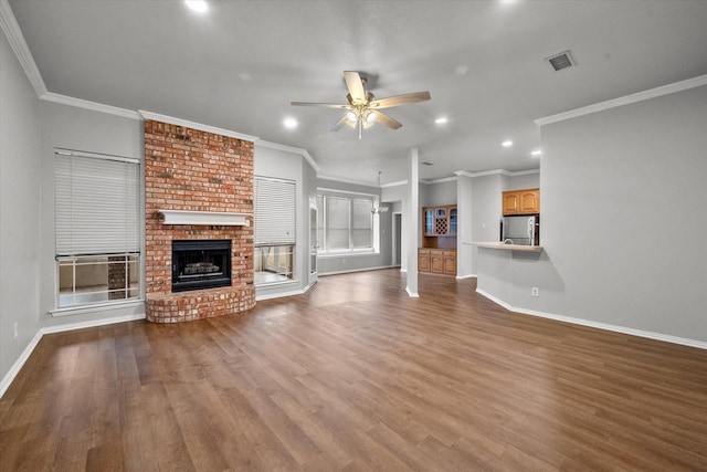 unfurnished living room with a brick fireplace, hardwood / wood-style flooring, ornamental molding, and ceiling fan